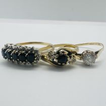 A group of three 9ct yellow gold rings. Featuring a dark sapphire and illusion set diamond trilogy