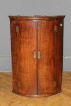 A George III oak barrel front hanging corner cupboard with four shelves and brass furniture. 99 x 66