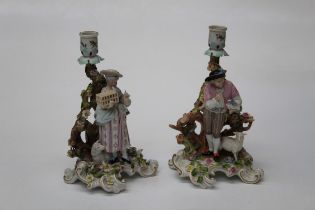 A pair of late 19th century German porcelain, polychrome decorated figural candlesticks, modelled as