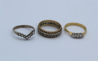 A collection of three rings comprising a diamond set three stone ring, stamped 18ct to the shank,