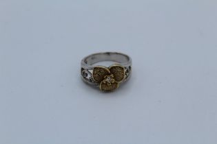 A flower and filigree formed dress ring on yellow and white metal, set with a cubic zirconia accent,