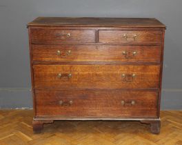 A George III oak chest of two short and three long drawers with swan neck drop handles, raised on