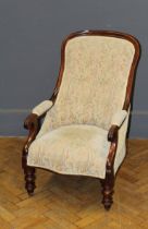 A Victorian mahogany framed parlour armchair with floral pastel upholstery, raised on turned