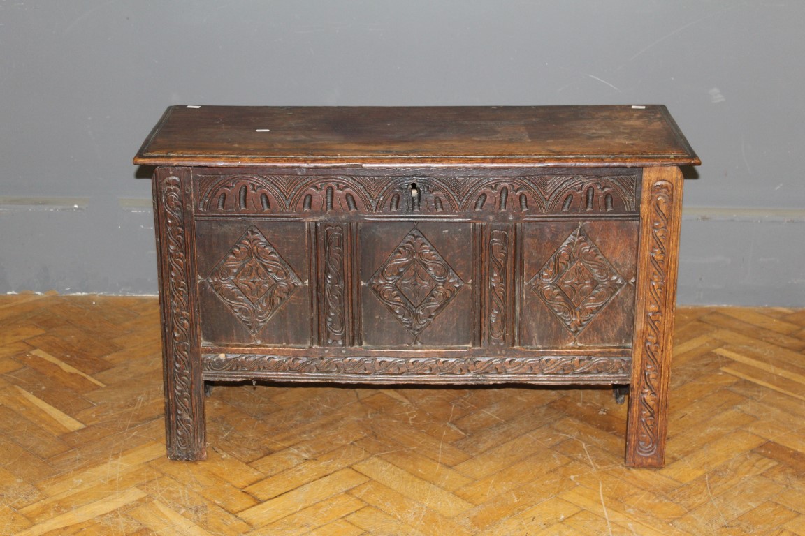 A late C17th/ early 18th oak coffer with three panel lozenge carved front, raised on stile