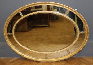 A 19th century gilt gesso oval wall mirror with gadrooned and beaded frame, enclosing eight