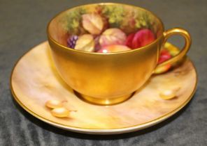 A Royal Worcester matched cabinet cup and saucer painted with fruit, the cup by N Deeley, the saucer