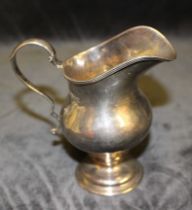 A Georgian style silver pear shaped cream jug with reeded border, double scroll handle and