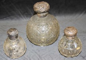 A cut glass globular scent bottle, the hinged silver cover repousse with foliate scrolls, 15cm
