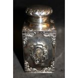 A Victorian silver rococo revival caddy and cover repousse with foliate scrolling cartouches and