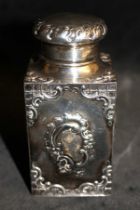 A Victorian silver rococo revival caddy and cover repousse with foliate scrolling cartouches and