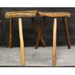 Two 19th century rustic elm milking stools, each shaped seat on three turned legs, one seat