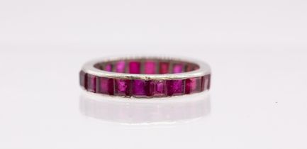 A ruby and white gold eternity band, comprising a row of calibre cut channel set rubies, each approx