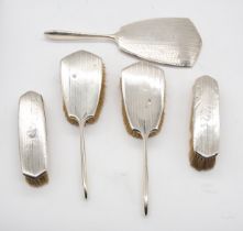 A George V silver mounted dressing table set to include four brushes and mirror, all with engraved