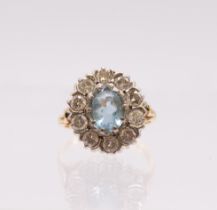 An aquamarine and diamond 18ct gold cluster ring, comprising an oval mixed cut aquamarine to the