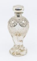 An Edwardian large cut glass baluster shaped scent bottle, the flower shaped silver collar chased