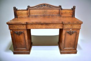 A Victorian walnut and mahogany pedestal sideboard with three single frieze drawers sitting on two