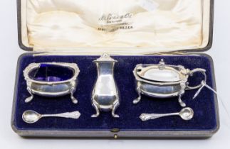 A cased George V silver condiment set consisting of mustard pot with blue glass liner, salt cellar