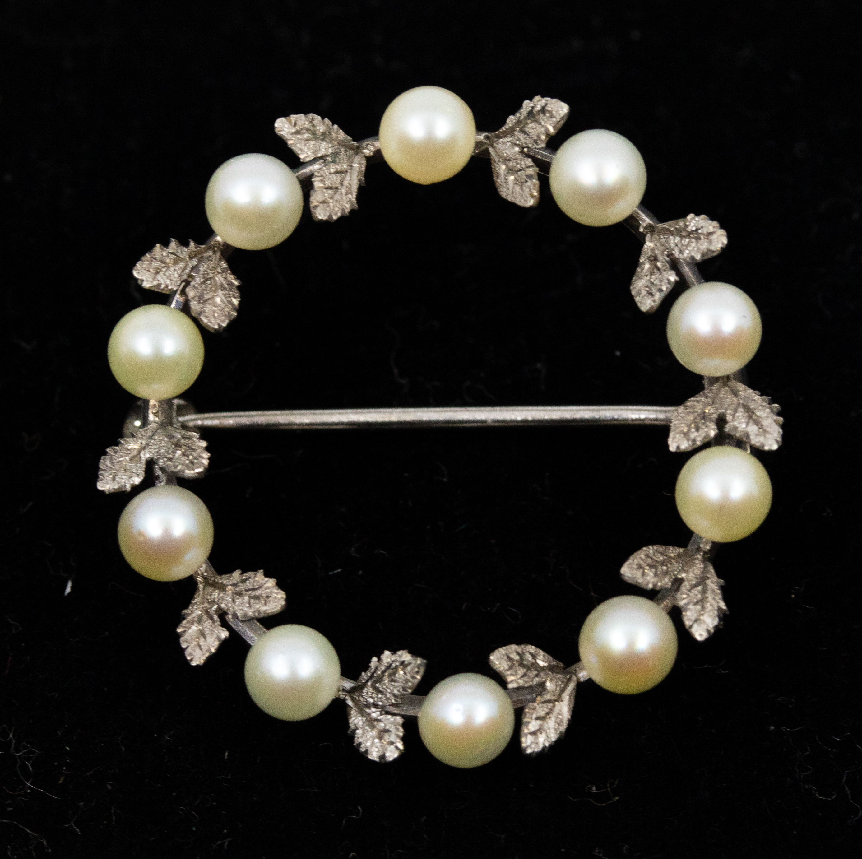 A pearl and white metal garland brooch, set with small cultured pearls and leaf decoration, diameter