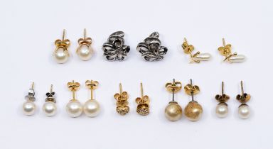 A collection of various gold earrings to include a pair of white metal floral earrings on screw