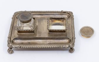 A late Victorian silver ink and pen stand, of rectangular form with gadroon border, on four scroll