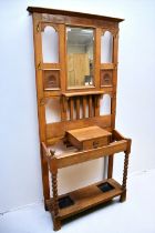 An Arts and Crafts style oak hall stand, having mirror to centre top, stick/umbrella stands to base,