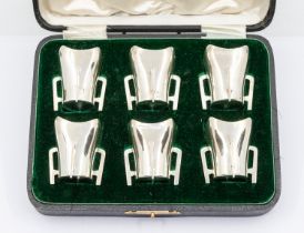 A set of six Edwardian silver tots in the form of plain miniature four handled tygs, hallmarked by