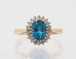 A 9ct gold blue topaz and diamond cluster ring, comprising an oval mixed cut topaz within a border