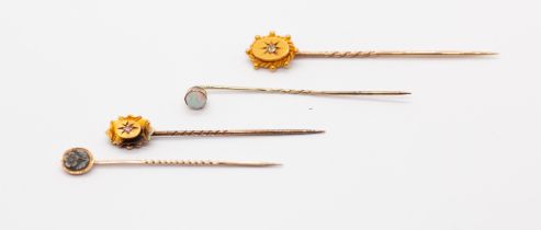A collection of four gold stick pins to include a Victorian diamond set 15ct gold pin, along with