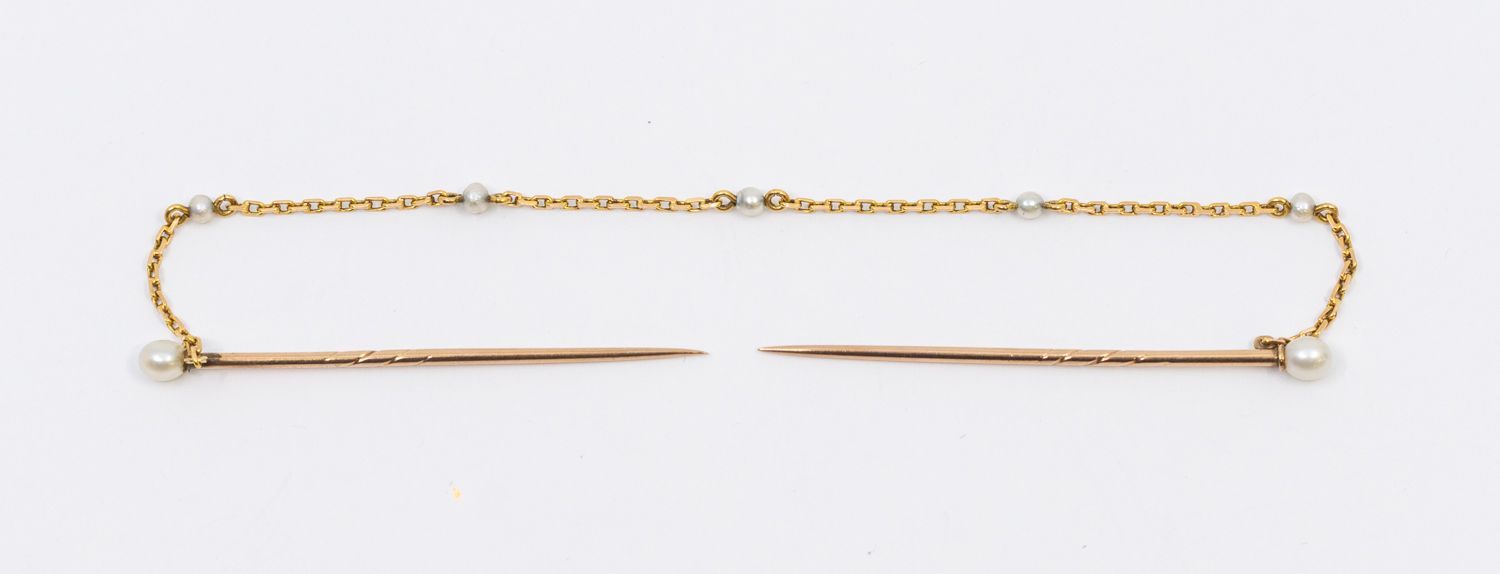 A double stick pin pearl set in 9ct gold, the pins with pearl set terminals connected by a fine