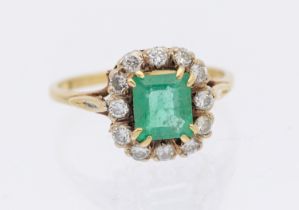 An emerald and diamond 18ct gold cluster ring, comprising an emerald cut emerald to the centre,