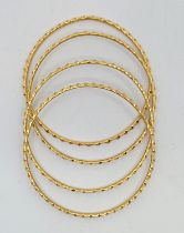 A set of four 18ct. gold bangles, with geometric decoration to exterior, import hallmarks for London