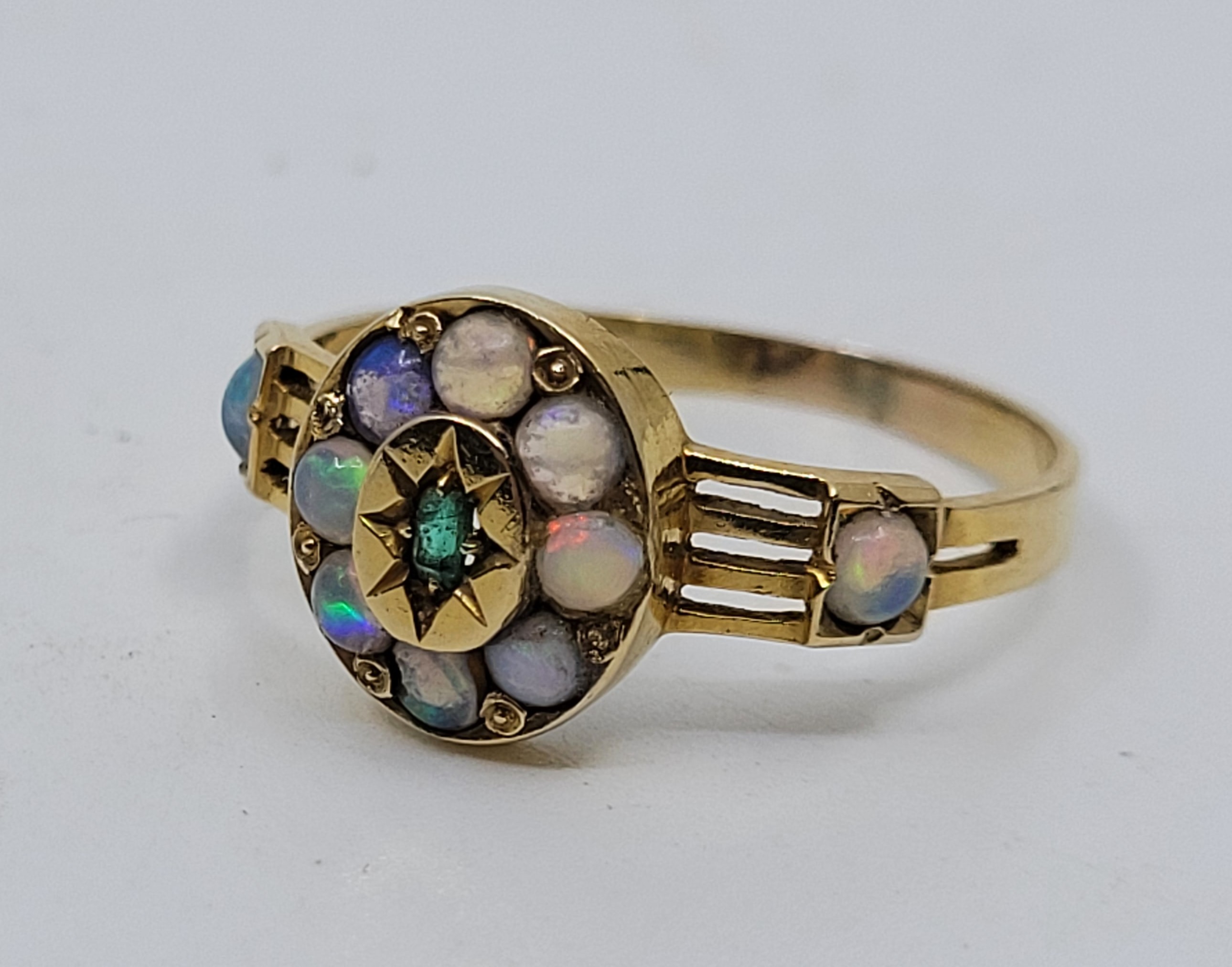 An 18ct gold, emerald and opal ring, the oval mount with raised centre illusion set single