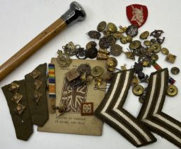 A silver handled walking cane and a collection of military cap badges and buttons