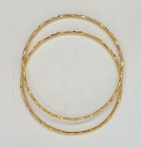 A pair of 18ct. gold bangles, decorated to exterior and side, import hallmarks for London 1980,