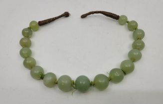 A string of green nephrite jade beads, the largest to centre diameter 21mm x length 19mm, strung