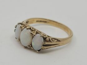 A 9ct. gold three stone opal ring, set three graduated oval cabochon opals above scrolled gallery,