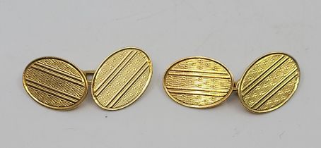 A pair of 18ct. gold oval engine turned cufflinks, chain fitting. (8.4g)