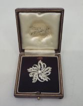 A precious white metal diamond floral brooch, set central round brilliant cut diamond (centre