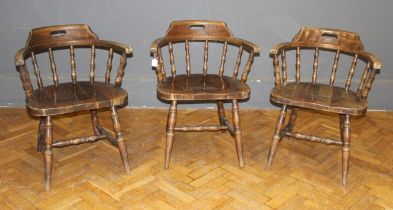 A set of three 20th century oak smoker’s bow armchairs, each with a carry handle to the shaped top
