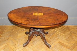A Victorian walnut, boxwood inlaid and strung oval snap top loo table, raised on leaf carved