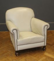 An early 20th century drawing room armchair, later upholstered in close studded cream hide, raised