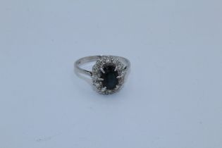 A sapphire and diamond cluster ring in white precious metal mount. Stamped 18ct to the shank.