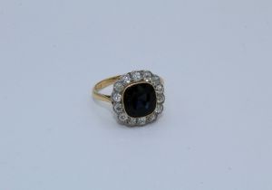 An early 20th century cushion dark blue sapphire and diamond cluster ring, featuring a central