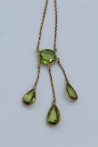 A yellow metal and peridot Edwardian negligee necklace featuring an oval peridot, with three pear