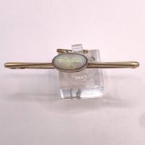 A "15ct" stamped opal set bar brooch. Featuring a single opal, with green play of colour, cut n