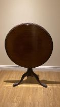 A late 19th Century mahogany tilt top side table with a single piece top having a carved rim on a