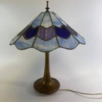 A Tiffany style table lamp with a leaded glass shade on a bronze stylised base. Approximately 40cm