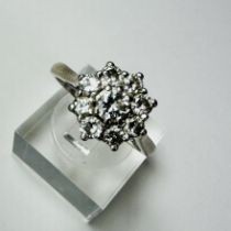 A diamond daisy ring. Set with nine round brilliant cut diamonds, the central stone an estimated 0.