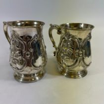 Two similar ornate Victorian sterling silver mugs. In baluster form with embossed floral decoration