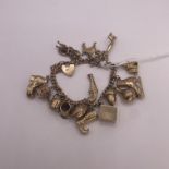 9ct Yellow Gold Charm Bracelet with 16 charms including bagpiper, opening church, ice skate, pistol,